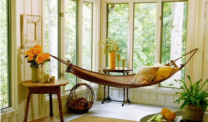 hammock in a corner with windows looking out to greenery