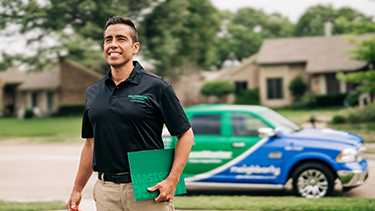 Smiling HouseMaster inspector walking in front of branded vehicle.